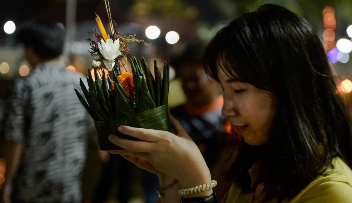 Seorang perempuan berdoa sebelum menghanyutkan 'krathong' untuk menandai festival Loy Krathong di sebuah danau di Narathiwat, Thailand,  Senin (11/11/2019). Loy Krathong dirayakan setiap tahun di seluruh Thailand sebagai penghormatan kepada dewi air. (Madaree TOHLALA / AFP)
