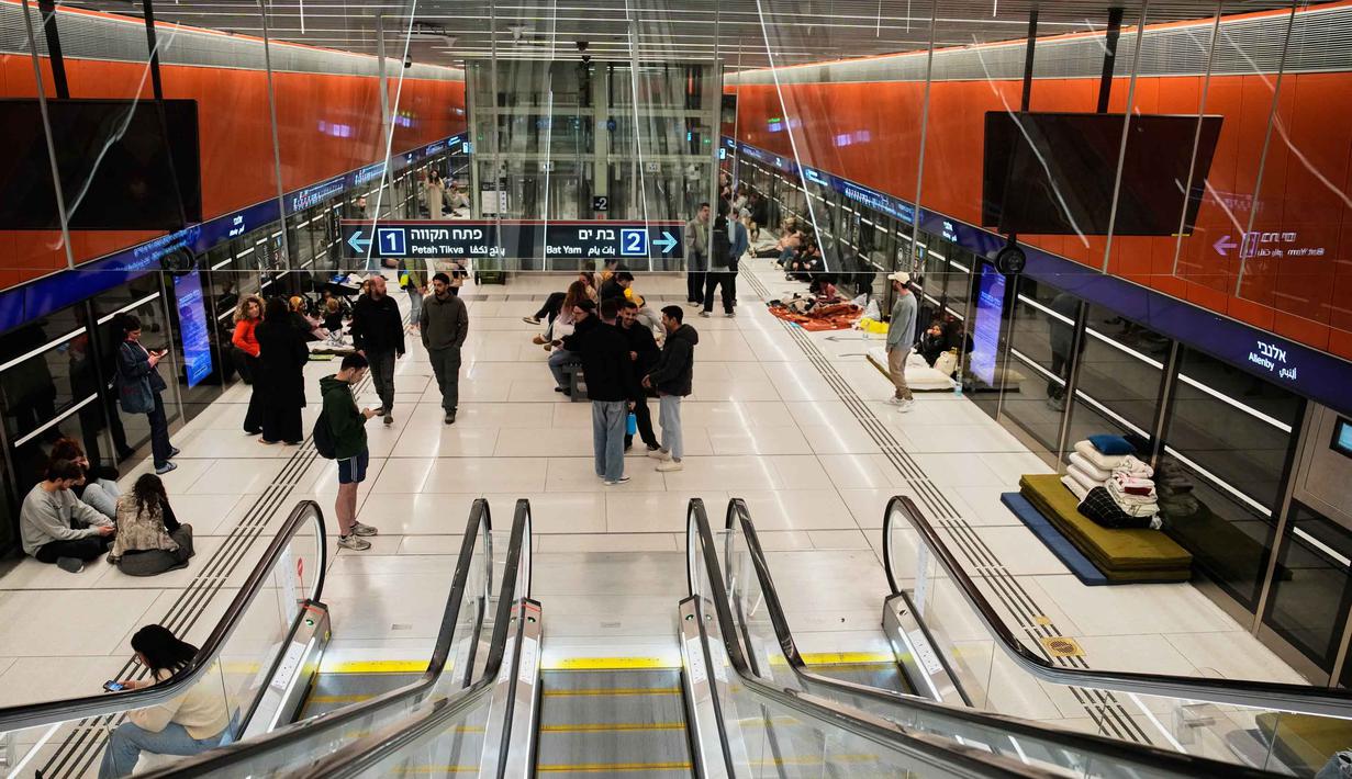 Pemerintah Israel telah menetapkan keadaan darurat, dan warga diminta berlindung saat sirene serangan udara berbunyi. Tampak dalam foto, orang-orang berlindung di stasiun metro bawah tanah saat sirene serangan udara memperingatkan datangnya rudal Iran di Tel Aviv, Israel, Sabtu, 7 Maret 2026. (AP Photo/Ohad Zwigenberg)