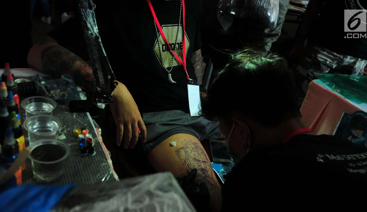 Seniman saat mentato bagian paha pengunjung dalam event tato di salah satu Mal di Jakarta, Sabtu (23/9). Event tato terbesar Se-Jakarta ini sudah ke empat kalinya di adakan. (Liputan6.com/Helmi Afandi)