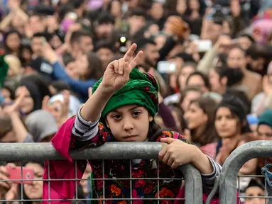 Seorang gadis mengacungkan dua jarinya saat memperingati Women's Day atau Hari Perempuan Internasional di Diyarbakir, Turki, Kamis (8/3). (ILYAS AKENGIN/AFP)