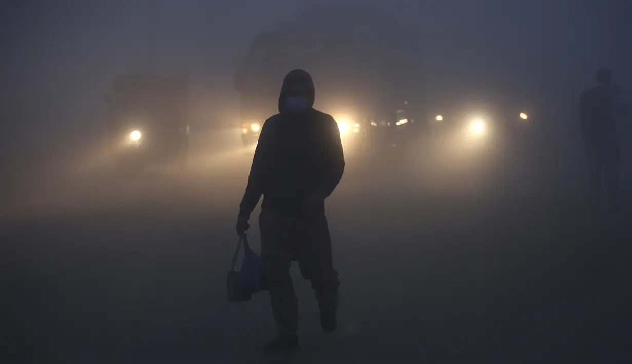 Kendaraan melaju dengan menyalakan lampu depan saat kabut tebal menyelimuti Lahore, Pakistan, 15 Desember 2021. Kabut tebal membuat kendaraan harus melaju lambat karena jarak pandang berkurang. (AP Photo/K.M. Chaudary)