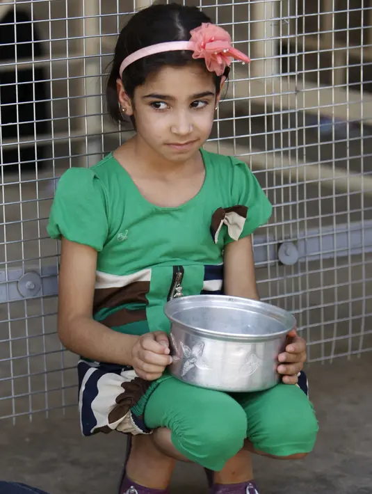 Ekspresi seorang anak perempuan saat menunggu makanan buka puasa gratis yang didistribusikan bagi yang membutuhkan selama bulan puasa di masjid Abdul Qadir al-Gailani, Baghdad, Rabu (24/6/2015). (REUTERS/Khalid al-Mousily)