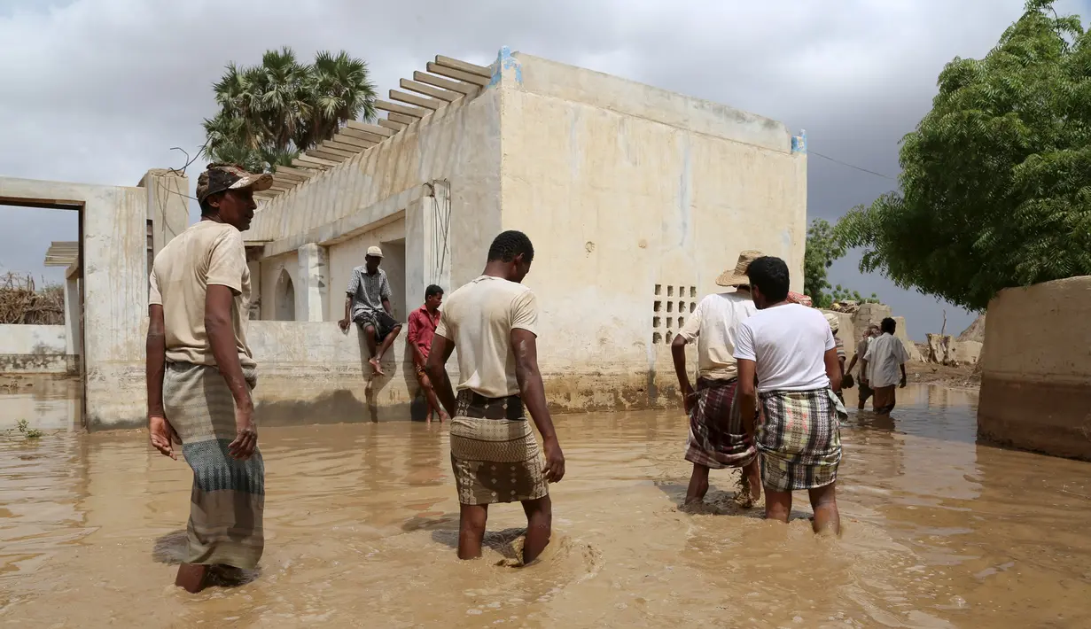 Sejumlah Warga melintasi banjir setelah hujan lebat di sebuah desa di provinsi Laut Merah Yaman, Houdieda, Jumat,  15 April 2016. (REUTERS/Abdul Jabbar Zeyad)