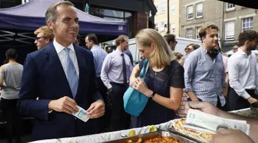 Gubernur Bank Inggris, Carney singgah untuk membeli makan siang di Whitecross Street Market di London, Selasa (13/9). Carney menunjukkan kepada penjual tentang kelebihan uang keluaran baru Bank Inggris. (REUTERS / Stefan Wermuth)