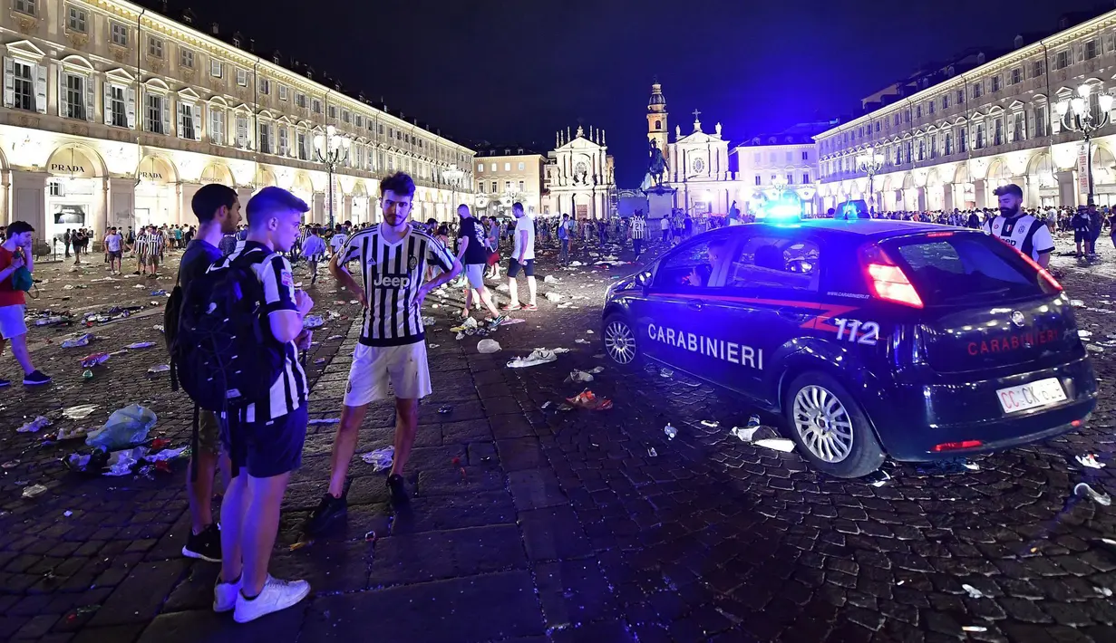 Suporter Juventus berdiri dekat kendaraan polisi di luar lokasi nonton bareng (nobar) final Liga Champions di Turin, Italia, (4/6). Ledakan terjadi beberapa saat usai Juventus mengalami kekalahan 1-4 dari Real Madrid. (Alessandro Di Marco/ANSA via AP)