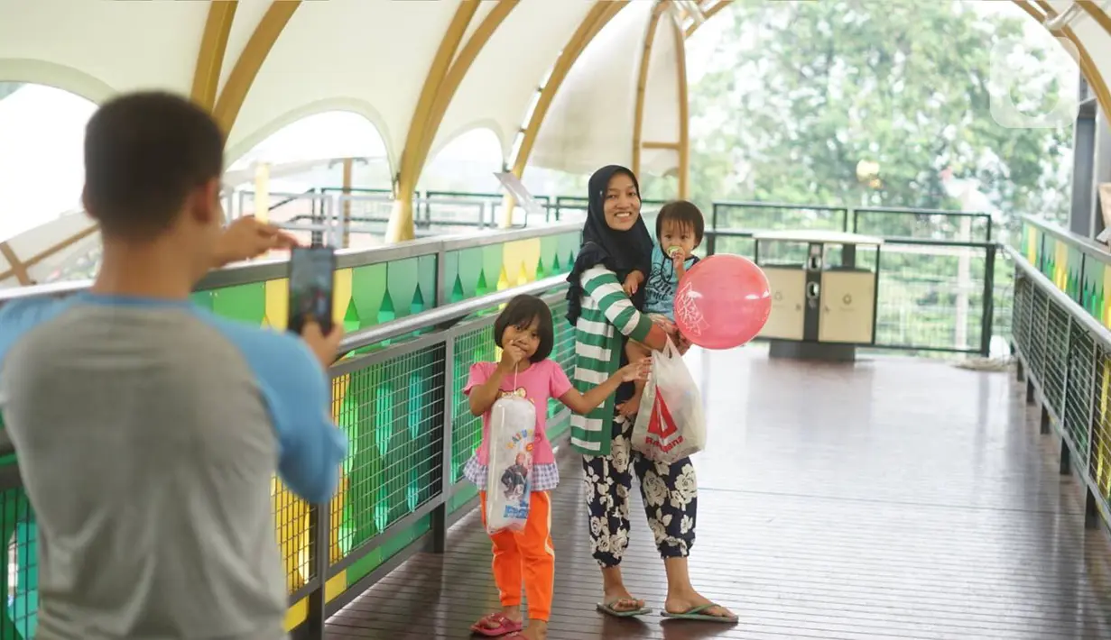 Warga berfoto di Jembatan Penyeberangan Orang (JPO) depan Stasiun Pasar Minggu, Jakarta, Kamis (9/1/2020). JPO yang juga dilengkapi dengan penutup dan lampu warna-warni tersebut menghubungkan Stasiun Pasar Minggu dengan pasar tradisional Pasar Minggu. (Liputan6.com/Immanuel Antonius)