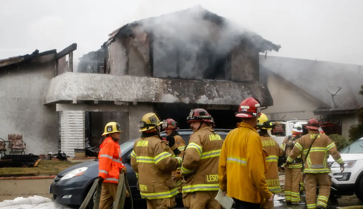 Petugas pemadam kebakaran berusaha memadamkan api di lokasi kecelakaan pesawat di sebuah rumah di Yorba Linda, California (3/2). (AP Photo/Alex Gallardo)