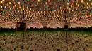 Seorang pengunjung difoto saat melihat ke dalam ruang cermin heksagonal berjudul 'Kusama's Peep Show or Endless Love Show' (1966) karya seniman Jepang Yayoi Kusama dalam pameran Yayoi Kusama: A Retrospective di Atrium Martin Gropius Bau, Berlin, Jerman, Selasa (19/5/2021). (John MACDOUGALL/AFP)