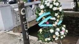 Sebuah karangan bunga berdiri dekat tiang lampu yang ditabrak mobil yang ditumpangi Ketua DPR Setya Novanto di Jalan Permata Berlian, Jakarta, Sabtu (18/11). Tiang lampu tersebut mendadak menjadi perhatian banyak masyarakat.  (Liputan6.com/Angga Yuniar)