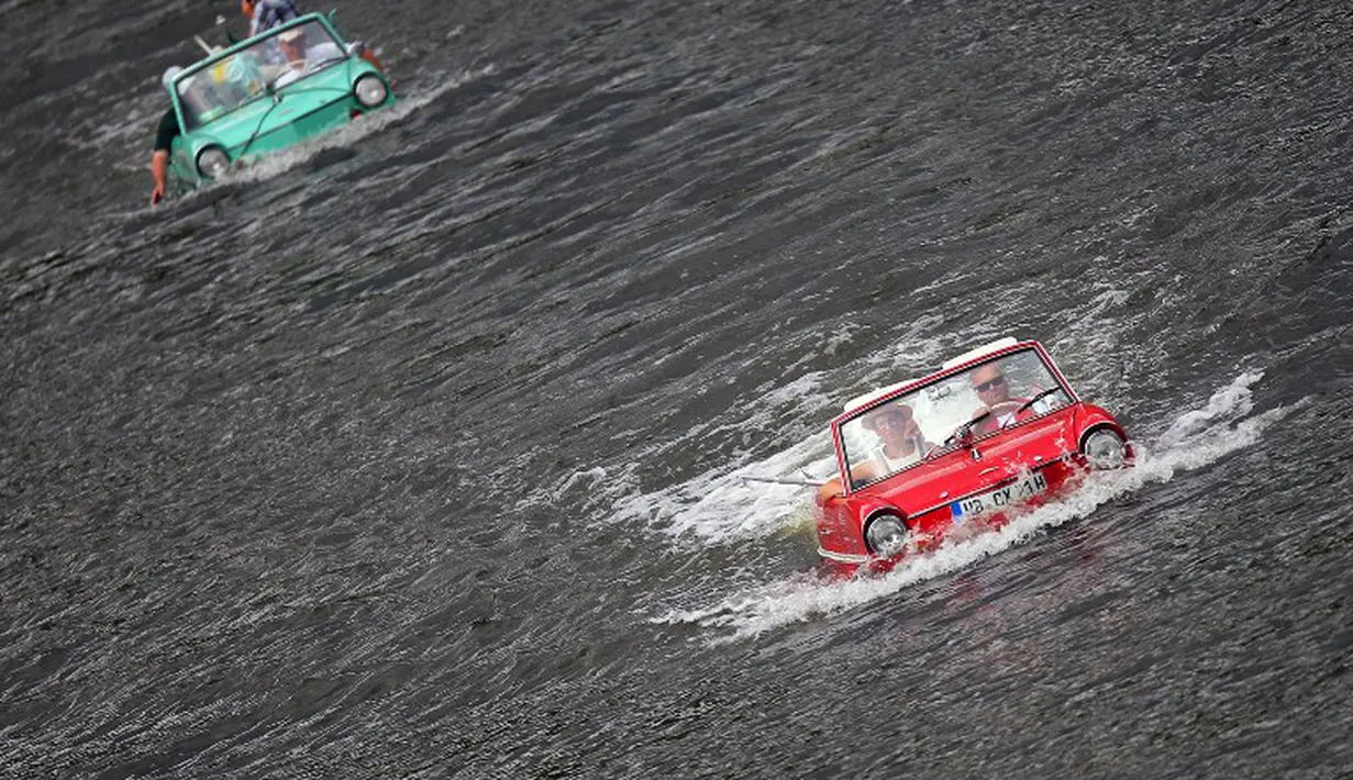 Sebuah mobil amphibi berwarna merah terlihat memimpin di depan dalam acara reli "Amphib 2014" yang berlangsung di  sungai Mosel, Jerman, Minggu (3/8/2014)  (AFP PHOTO/Fredrik VON Erichse)