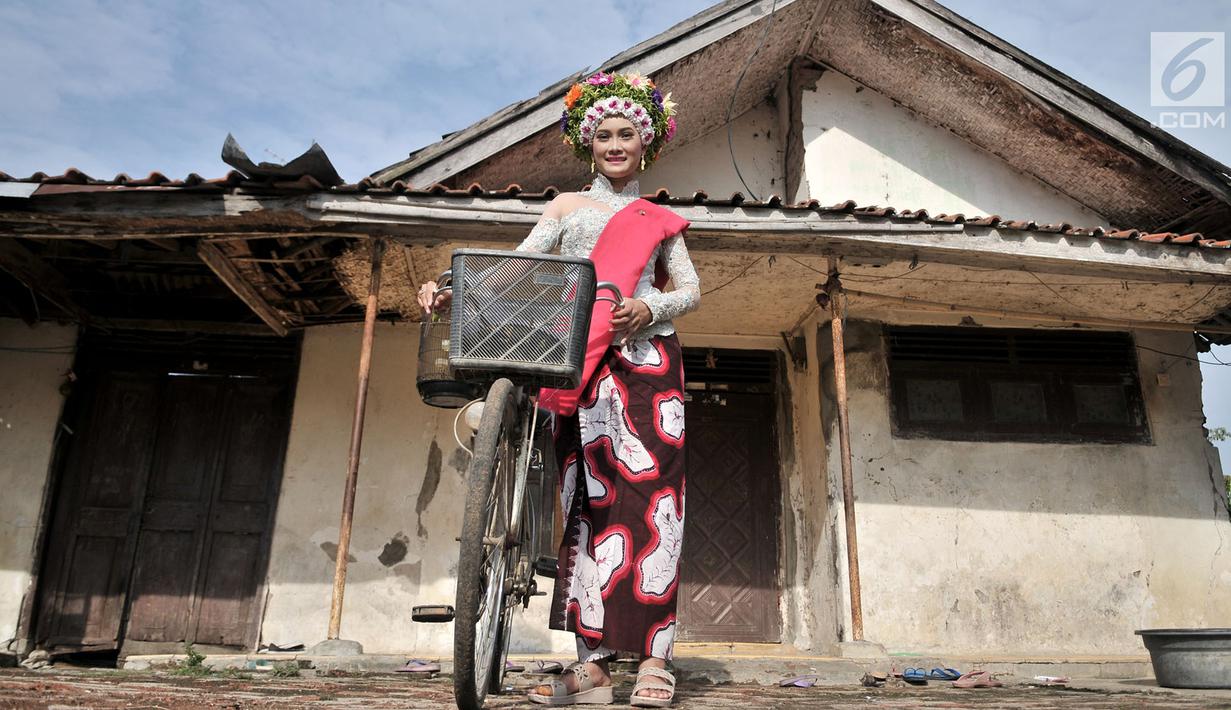 Seorang gadis menggunakan sepeda saat hendak menuju titik kumpul untuk mengikuti upacara adat Ngarot di Desa Lelea, Indramayu, Jawa Barat, Rabu (19/12). Ngarot merupakan tradisi yang diikuti gadis 'perawan'. (Merdeka.com/Iqbal Nugroho)