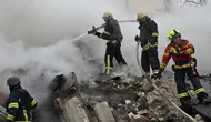 Petugas penyelamat dan pemadam kebakaran Ukraina membersihkan puing-puing di lokasi serangan rudal di Kharkiv pada 23 Januari 2024. (SERGEY BOBOK/AFP)
