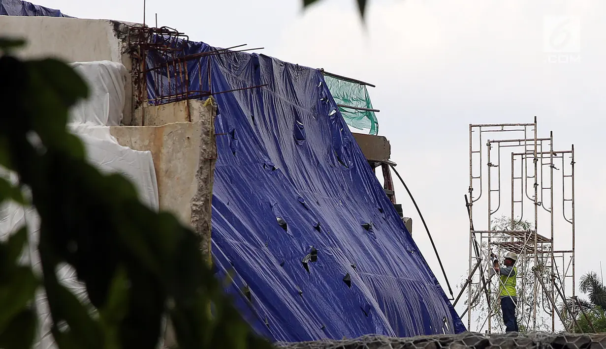 Petugas melihat sisa robohnya bangunan proyek Apartemen Pakubuwono Spring 3 yang ditutupi terpal di Jalan Teuku Cut Nyak Arief, Jakarta, Rabu (27/12). Akibat insiden ini, tiga orang tewas. (Liputan6.com/JohanTallo)