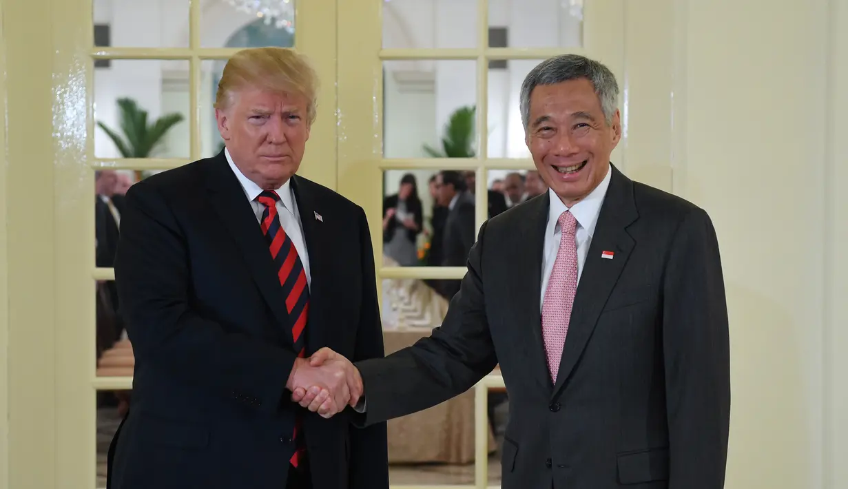 Presiden AS Donald Trump (kiri) berjabat tangan dengan PM Singapura Lee Hsien Loong (kanan) saat menerima jamuan makan siang di Istana Negara Singapura, Senin (11/6). Acara makan siang ini adalah agenda pertama Trump di Singapura. (SAUL LOEB/AFP)