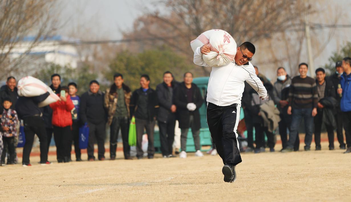 Seorang petani berlari sambil memanggul sekarung biji-bijian dalam sebuah perlombaan di Yaogou, Sihong, Suqian, Provinsi Jiangsu, China, 27 Desember 2020. Tahun ini, ada delapan perlombaan menarik yang dekat dengan kehidupan petani. (Xinhua/Xu Changliang)