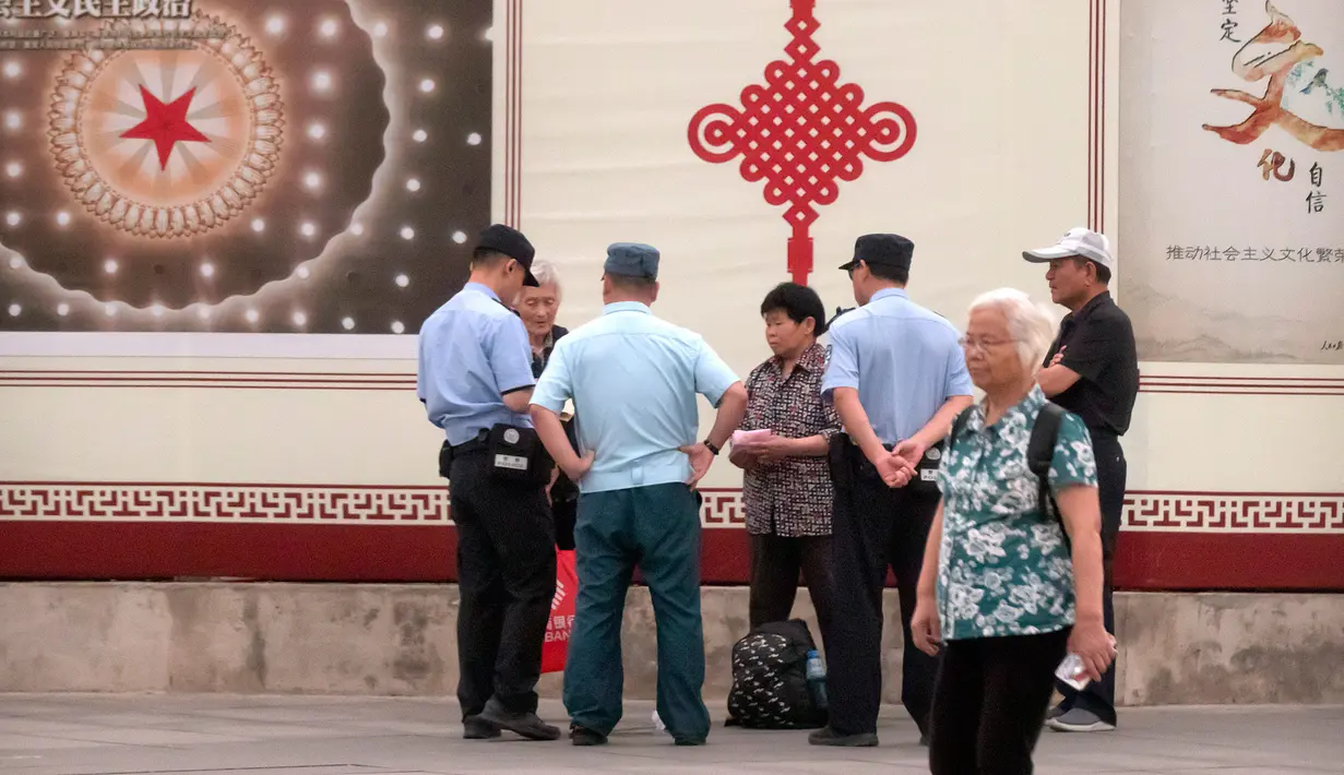 Petugas keamanan memeriksa dokumen orang-orang di sepanjang jalan dekat Lapangan Tiananmen di Beijing (4/6/2019). Pemerintah China meningkatkan keamanan di sekitar Lapangan Tiananmen di pusat Beijing jelang peringatan tragedi Tiananmen 1989. (AP Photo/Mark Schiefelbein)