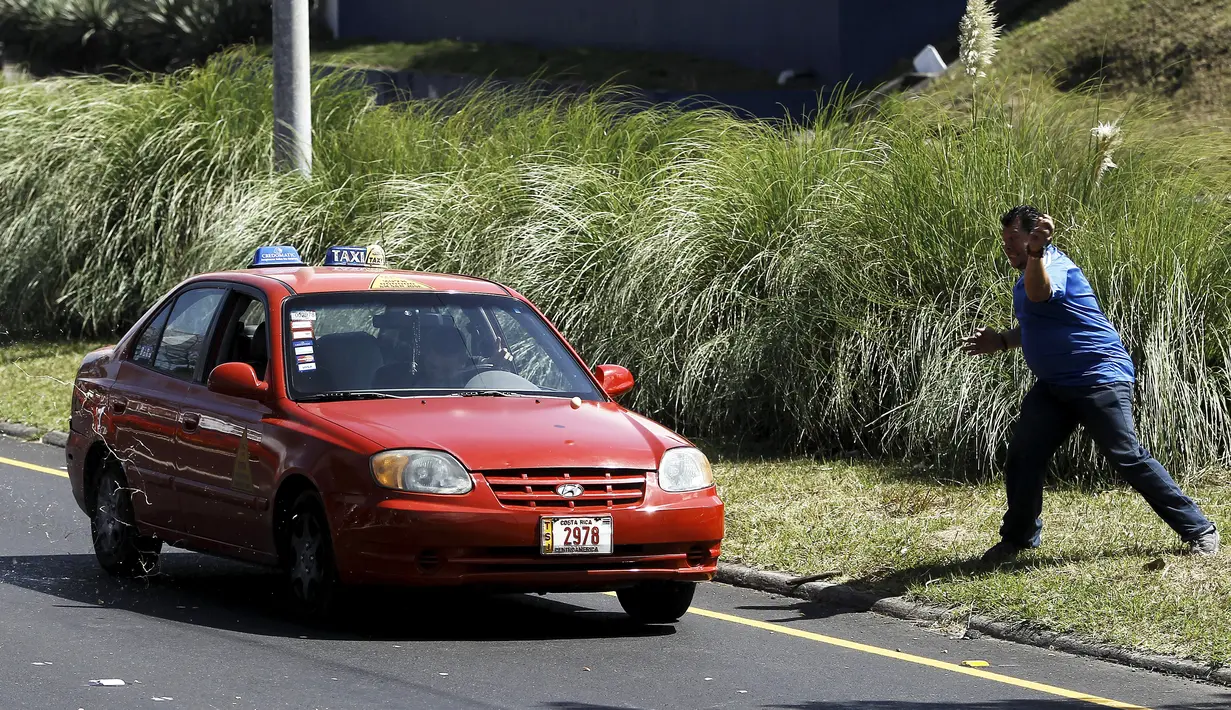 Seorang sopir taksi melemparkan telur ke mobil rekan mereka yang menolak ikut unjuk rasa di San Jose, Senin (1/2).  Mereka melakukan protes terhadap taksi Uber yang mulai beroperasi di Kosta Rika. (REUTERS/Juan Carlos Ulate) 