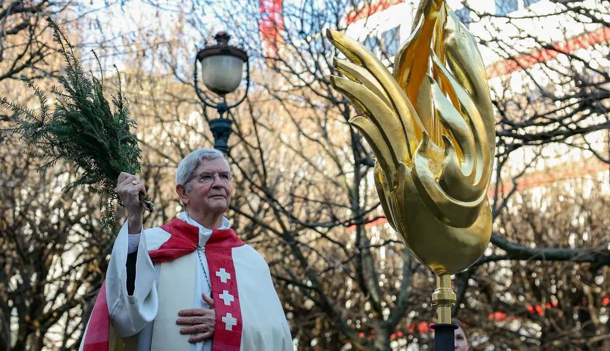 Uskup Agung Paris Laurent Ulrich memberkati ayam jantan itu dengan sayap emas seperti api sebelum diangkat ke tempatnya di puncak menara katedral setinggi 96 meter (315 kaki). (Thomas SAMSON / AFP)