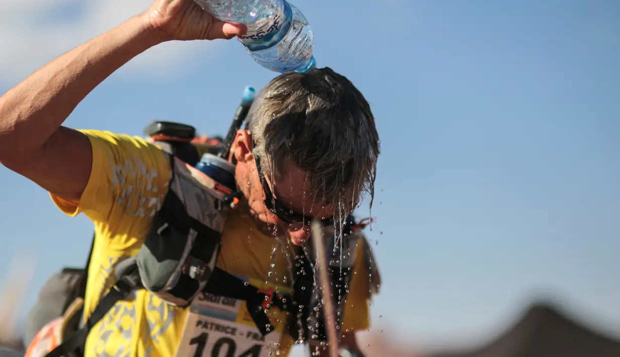 Seorang peserta mendinginkan kepalanya dengan menyiramkan air saat mengikuti kompetisi Marathon des Sables ke-33 di gurun Sahara, Maroko (11/4). (AP Photo / Mosa'ab Elshamy)