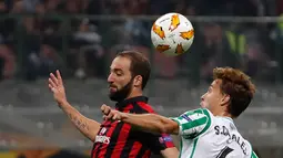 Pemain AC Milan, Gonzalo Higuain (kiri) berebut bola dengan pemain Real Betis Sergio Canales saat bertanding dalam Grup F Liga Europa di Stadion San Siro, Milan, Italia, Kamis (25/10). AC Milan kalah 1-2. (AP Photo/Antonio Calanni)