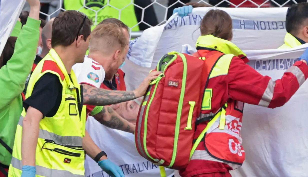 Kapten Timnas Denmark, Simon Kjaer pun sempat menghampiri Eriksen saat dibawa keluar lapangan. Dan Eriksen pun terlihat sudah bisa merespon panggilan Simon Kjaer yang berada disampingnya. (Foto: AFP/Pool/Hannah McKay)