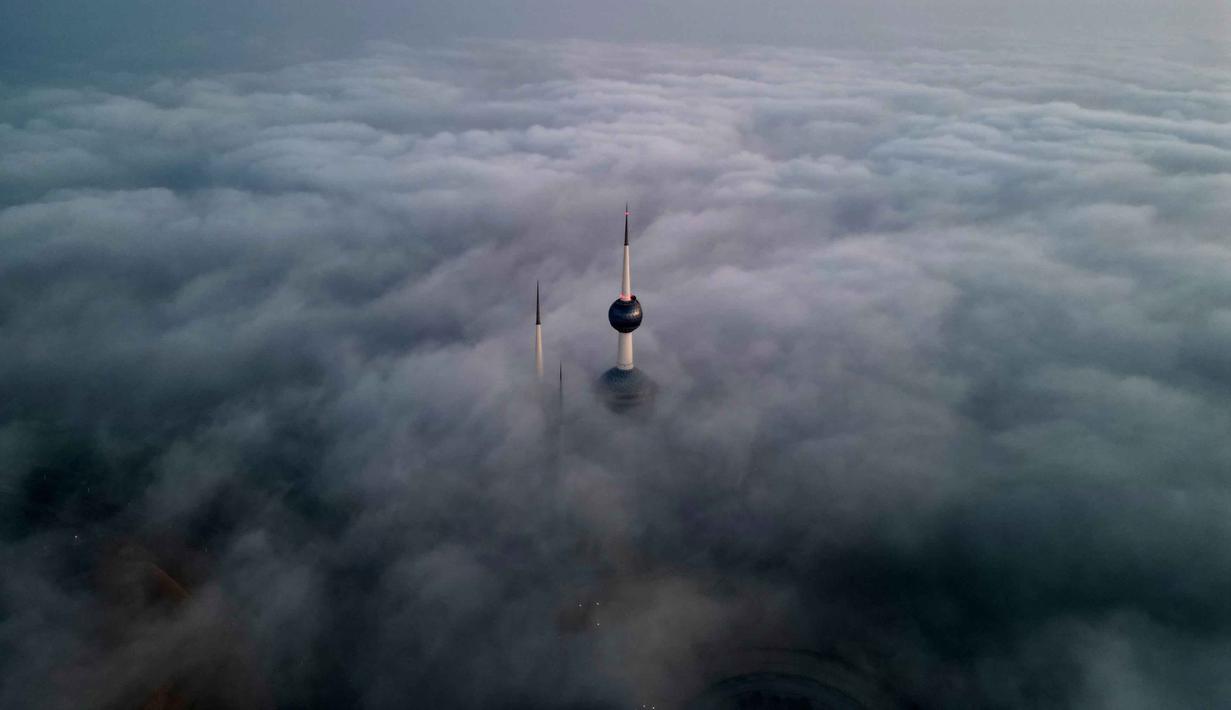 Foto udara ini memperlihatkan gedung-gedung tinggi Kuwait yang tertutup kabut pagi, pada Minggu 9 November 2025. Kabut tebal menutupi cakrawala Kota Kuwait pada Minggu 9 November 2025 pagi waktu setempat. (YASSER AL-ZAYYAT/AFP)