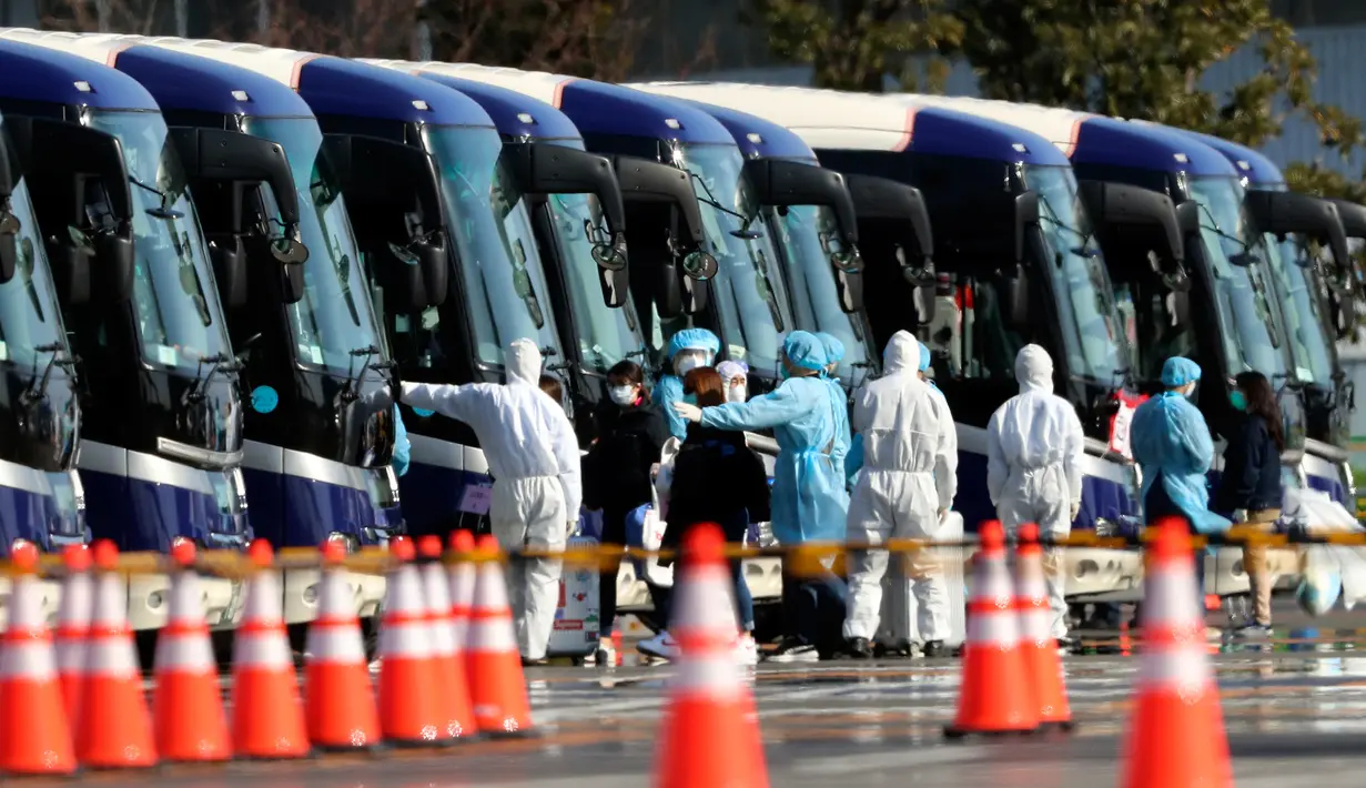 Petugas mengawal penumpang asing yang turun dari kapal pesiar Diamond Princess yang dikarantina di Yokohama, Jepang, Jumat (21/2/2020). Ratusan orang yang dinyatakan negatif virus corona (COVID-19) berangsur meninggalkan kapal. (AP Photo/Eugene Hoshiko)