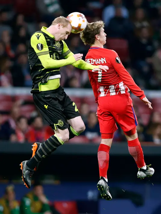 Pemain Atletico Madrid Antoine Griezmann berebut bola di udara dengan pemain Sporting Lisbon Jeremy Mathieu saat pertandingan Liga Europa di stadion Metropolitano, Madrid (5/4). (AP Photo / Francisco Seco)