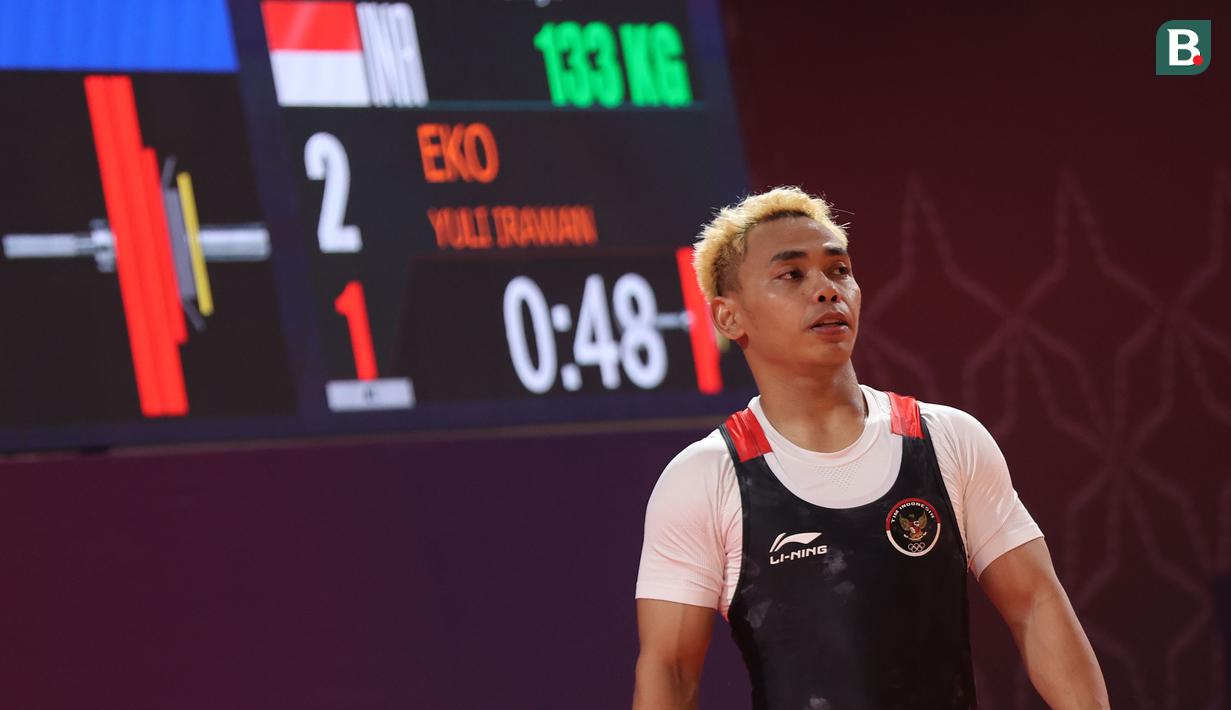 Lifter Indonesia, Eko Yuli Irawan mempersembahkan medali emas ke-54 bagi Kontingen Indonesia di SEA Games 2023 Kamboja dari kelas 61 kg putra. Dalam lomba yang digelar di Taekwondo Hall Olympic Complex, Phnom Penh, Kamboja, Sabtu (13/5/2023) sore WIB, Eko Yuli Irawan total mengangkat barbel seberat 303 kg, hasil dari 133 kg pada angkatan snatch dan 170 kg dari clean and jerk. Medali perak direbut oleh lifter Filipina, John Februar Manguroban Ceniza dengan angkatan total 297 kg dan perunggu menjadi milik lifter Thailand, Teerapat Chonchuen dengan angkatan total 296 kg. Eko Yuli Irawan juga mampu memecahkan rekor SEA Games atas namanya sendiri pada angkatan clean and jerk 170 kg yang sebelumnya dibuat pada SEA Games Filipina dengan 169 kg. (Bola.com/Abdul Aziz)