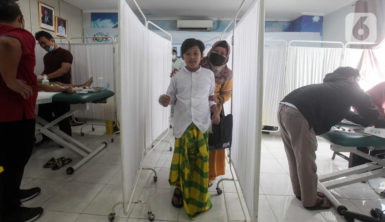 Seorang anak didampingi orang tuanya usai mengikuti sunatan massal yang diselenggarakan oleh Pemerintah Provinsi DKI Jakarta di RSUD Kebayoran Baru, Kamis (26/6/2025). (Liputan6.com/Herman Zakharia)