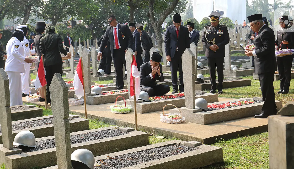 Presiden Joko Widodo bersama Wakil Presiden Ma'ruf Amin berdoa setelah melakukan tabur bunga usai upacara peringatan Hari Pahlawan Nasional di Taman Makam Pahlawan (TMP) Utama Kalibata, Jakarta Selatan, Minggu (10/11/2019). (Liputan6.com/Herman Zakharia)