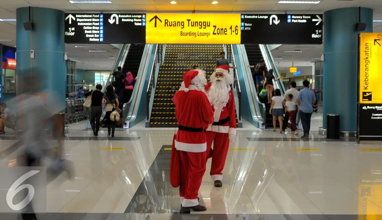 Dua Santa Claus saat ingin memberikan hadiah kepada penumpang di Bandara Soekarno Hatta, Tangerang, Banten, Selasa (22/12). Sejumlah orang berkostum santa claus membagikan coklat kepada penumpang yang berada dibandara. (Liputan6.com/Faisal R Syam)