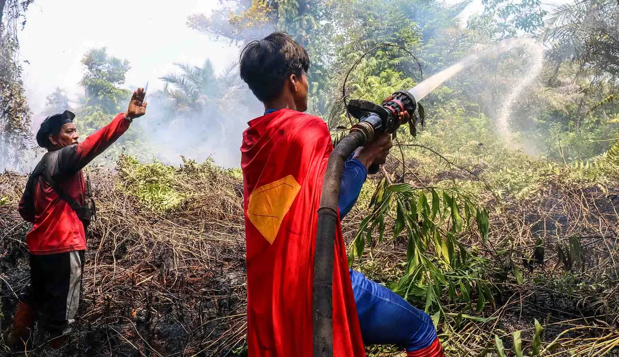 Pelajar bernama Rudiansyah dengan mengenakan kostum Superman membantu memadamkan kebakaran hutan dan lahan di Petuk Katimpun, Palangkaraya, Kalimantan Tengah, 17 Agustus 2026. (AFP/ Reina)