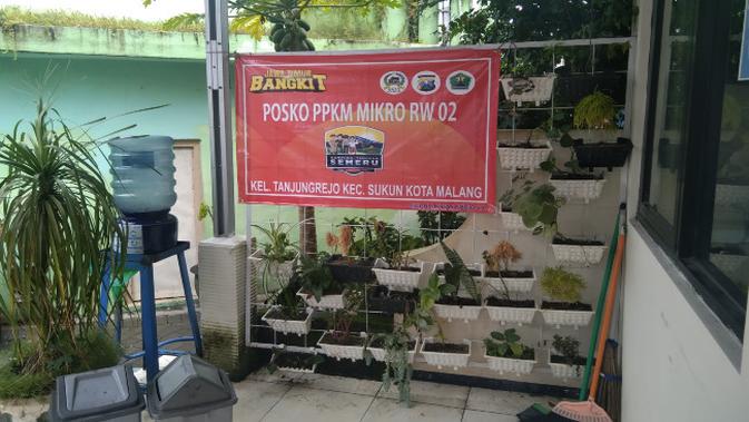 Sebuah spanduk bertuliskan posko PPKM Mikro di depan sebuah balai RW di Kota Malang. Setiap posko mulai tingkat RT sampai kecamatan mendapat dukungan dana operasional (MCW)