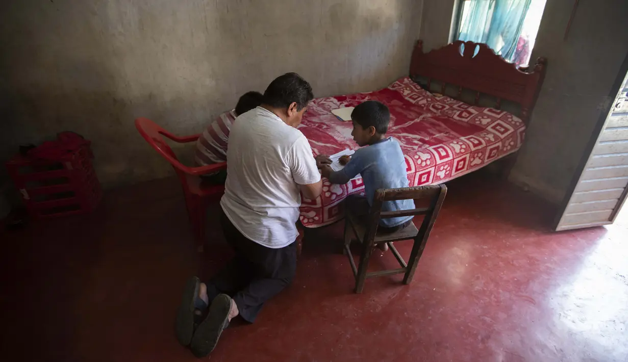 Agustin Vazquez membantu putra-putranya Samuel dan Hector mengerjakan tugas sekolah di tengah pandemi COVID-19 di rumah mereka, Nuevo Yibeljoj, Chiapas, Meksiko, 11 September 2020. (AP Photo/Eduardo Verdugo)