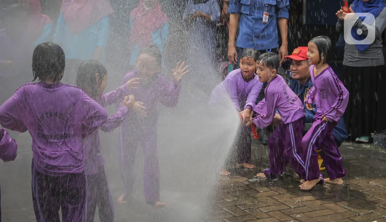Petugas pemadam kebakaran (Damkar) Kota Tangerang membantu siswa Taman Kanak-Kanak (TK) menyemprotkan air untuk memadamkan api saat edukasi pengenalan profesi Damkar di Kota Tangerang, Banten (22/11/2023). (Liputan6.com/Angga Yuniar)