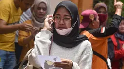 Seorang wanita melakukan panggilan telepon sambil memegang foto korban kerusuhan Stadion Kanjuruhan menangis saat menunggu di Rumah Sakit Saiful Anwar, Malang, Jawa Timur, Minggu (2/10/2022). Hingga saat ini, dilaporkan sebanyak 129 orang meninggal dunia dalam kejadian tersebut. (AP Photo/Trisnadi)