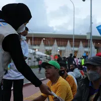 Relawan yang bertugas menjadi Satgas Prokes PON XX membagikan masker kain kepada warga yang ada di dalam kawasan Stadion Lukas Enembe (Dok. BNPB)