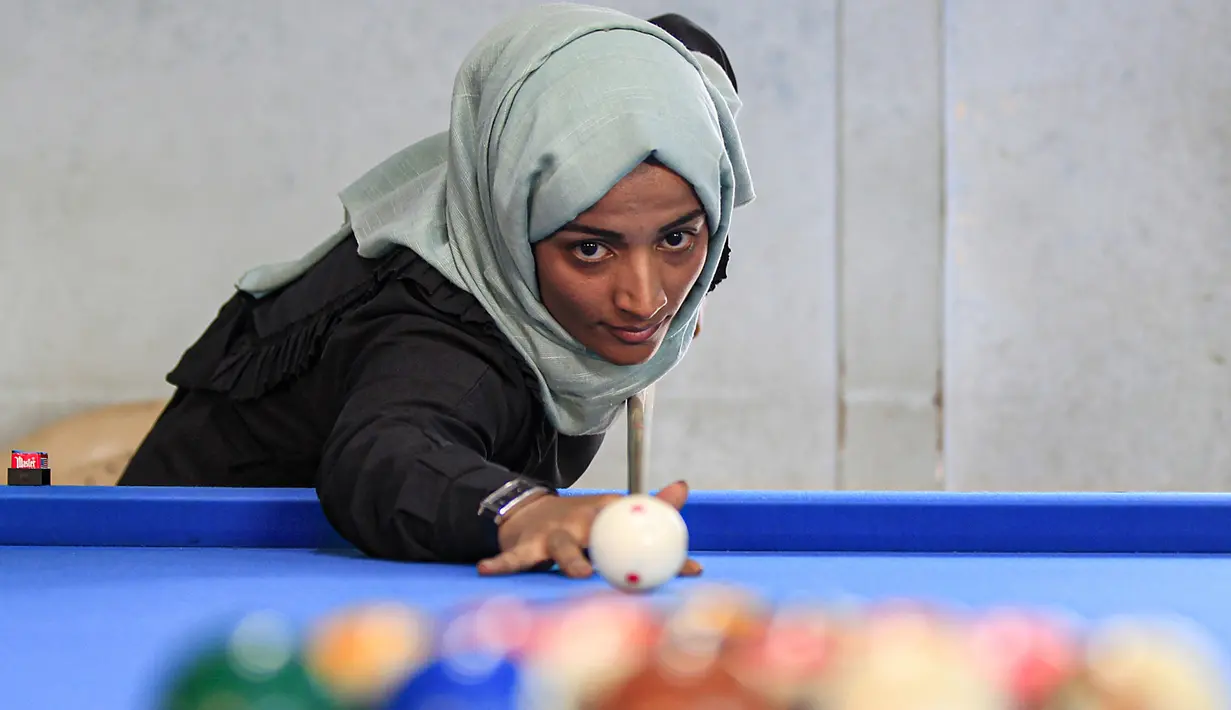 Seorang wanita membidik bola saat mengikuti kejuaraan biliar lokal di sebuah gedung olahraga di ibu kota  Sanaa, Yaman  (16/12/2019).  (AFP/Mohammed Huwais)