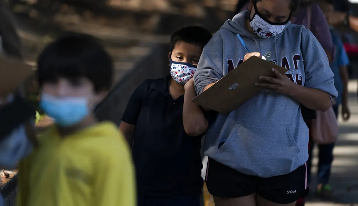 Eric Aviles (6) bersandar pada ibunya Catherine saat antre untuk menerima vaksin COVID-19 Pfizer di klinik vaksin pediatrik di Willard Intermediate School, Santa Ana, California, Amerika Serikat, 9 November 2021. AS gelar vaksinasi COVID-19 untuk anak-anak berusia 5-11 tahun. (AP Photo/Jae C. Hong)