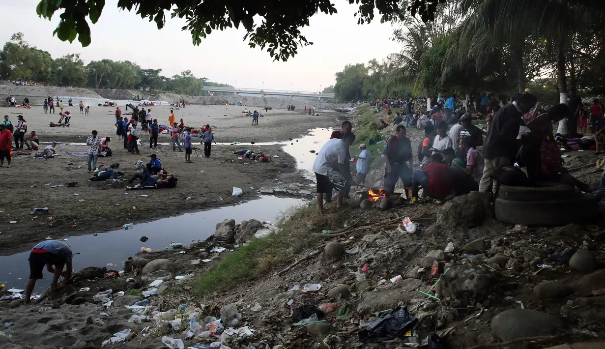 Migran Amerika Tengah beristirahat setelah menyeberangi Sungai Suchiate dengan berjalan kaki dari Guatemala ke Meksiko, Ciudad Hidalgo, Meksiko, Senin (20/1/2020). Lebih dari seribu migran Amerika Tengah berjalan massal untuk menuju Amerika Serikat. (AP Photo/Marco Ugarte)