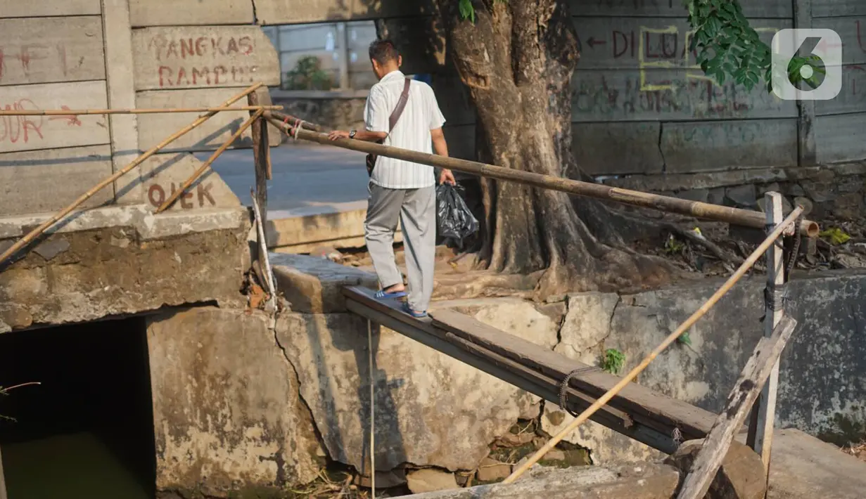 Pejalan kaki melintasi jembatan saat akan melewati tembok berlubang di Terminal Kampung Rambutan, Jakarta, Kamis (19/12/2019). Jauhnya akses bagi pejalan kaki menjadikan tembok berlubang tersebut pintu alternatif untuk keluar dan masuk Terminal Kampung Rambutan. (Liputan6.com/Immanuel Antonius)