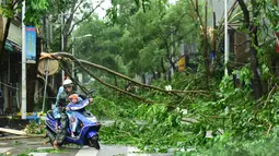 Pengendara motor bersama seorang memutar balik setelah sebuah pohon besar menutupi jalanan akibat Topan Sarika di Qionghai, Provinis Hainan, Tiongkok, (18/10). (REUTERS/Stringer)