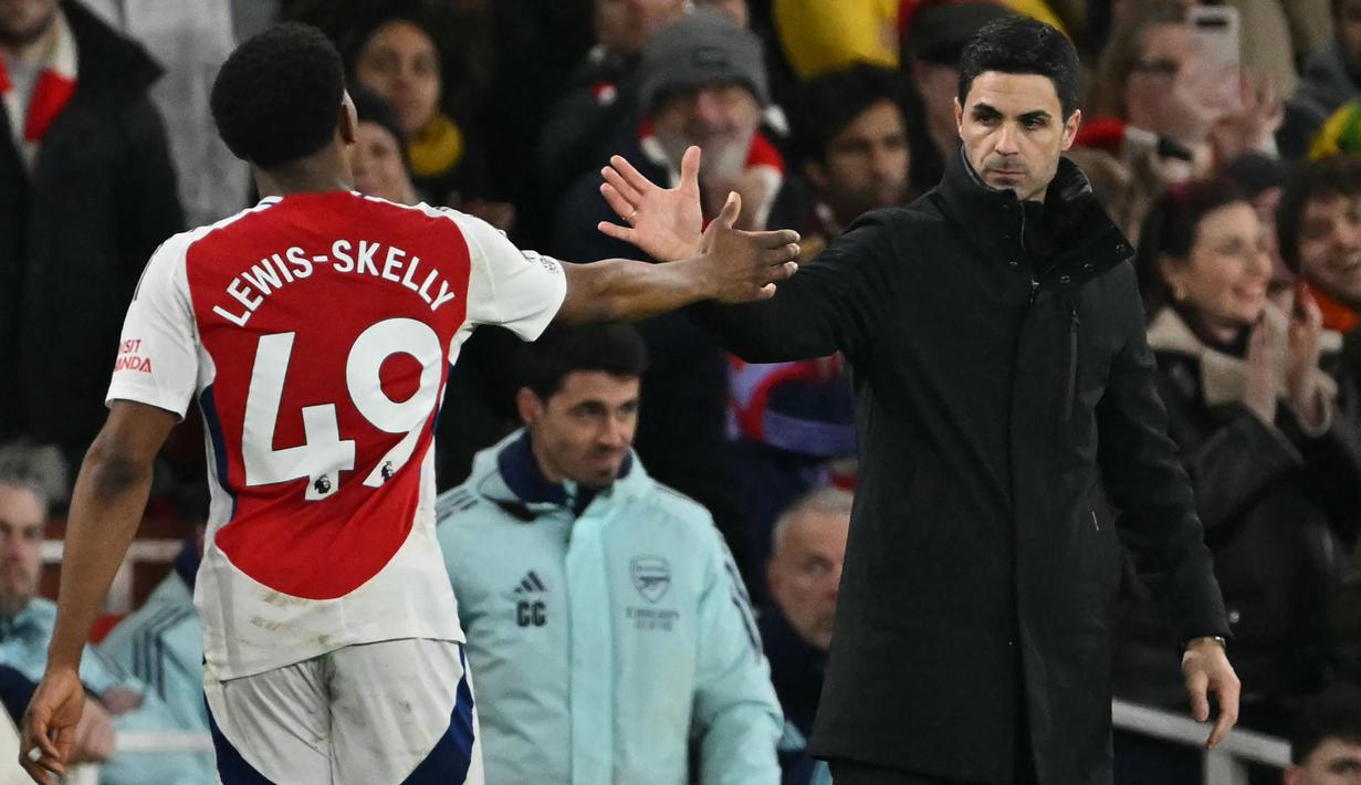 Pemain Arsenal, Myles Lewis-Skelly melakukan tos dengan pelatih Mikel Arteta saat digantikan dalam laga lanjutan Liga Inggris 2024/2025 melawan Manchester City di Emirates Stadium, London, Minggu (03/02/2025). (AFP/Glyn Kirk)