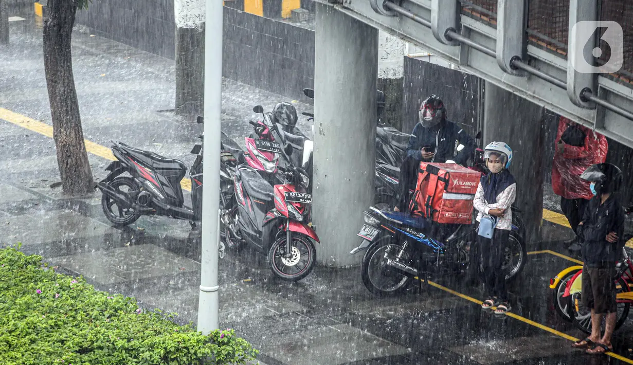 Warga berteduh saat turun hujan di Jalan Jenderal Sudirman, Jakarta, Minggu (18/10/2020). Badan Meteorologi, Klimatologi, dan Geofisika (BMKG) menyatakan musim hujan berlangsung mulai Oktober dan diprediksi mencapai puncaknya pada Januari hingga Februari 2021. (Liputan6.com/Faizal Fanani)