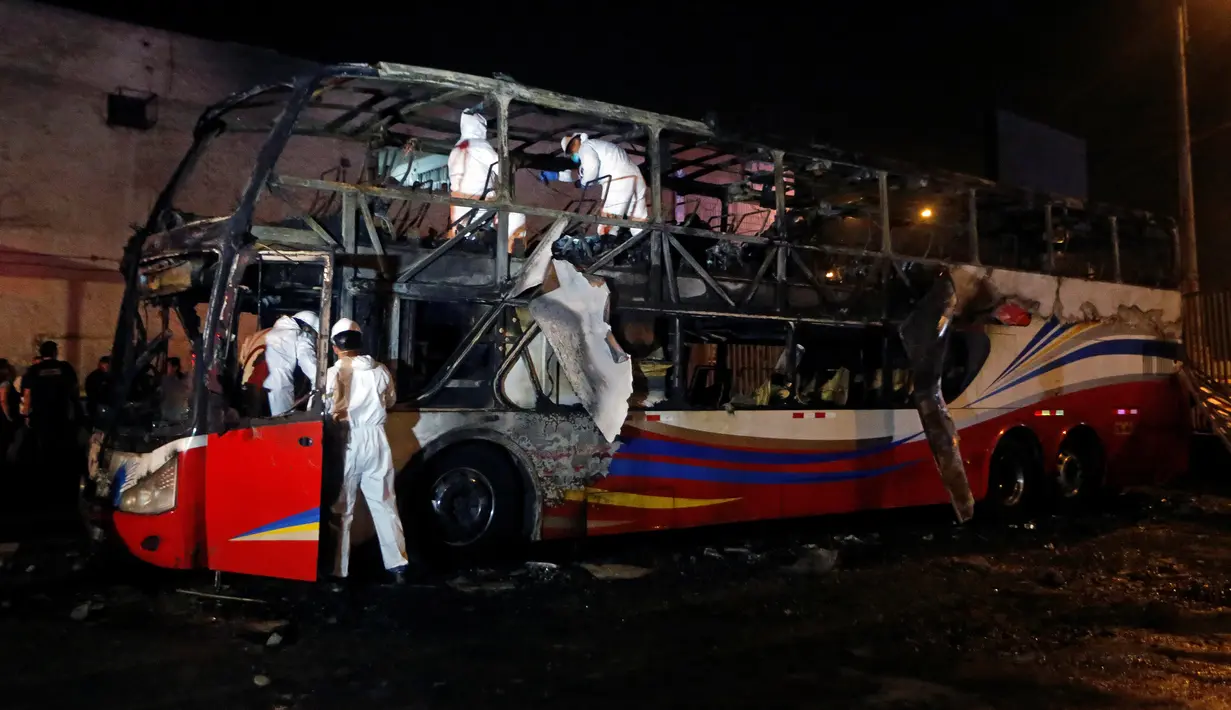Para petugas memeriksa kerangka  bus bertingkat yang hangus terbakar di terminal bus antarprovinsi, kota Lima, Peru, Minggu (31/3). Delapan kendaraan pemadam kebakaran dikerahkan dalam insiden kebakaran alat transportasi publik terparah di Lima sepanjang sejarah. (REUTERS/Stringer)