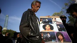 Penggemar membawa poster untuk mengenang penyanyi legendaris dunia, Prince, di Los Angeles, California, Kamis (21/4). Prince ditemukan dalam posisi telentang dan keadaannya sudah tak bernafas di Paisley Park, Minnesota. (REUTERS/Lucy Nicholson)
