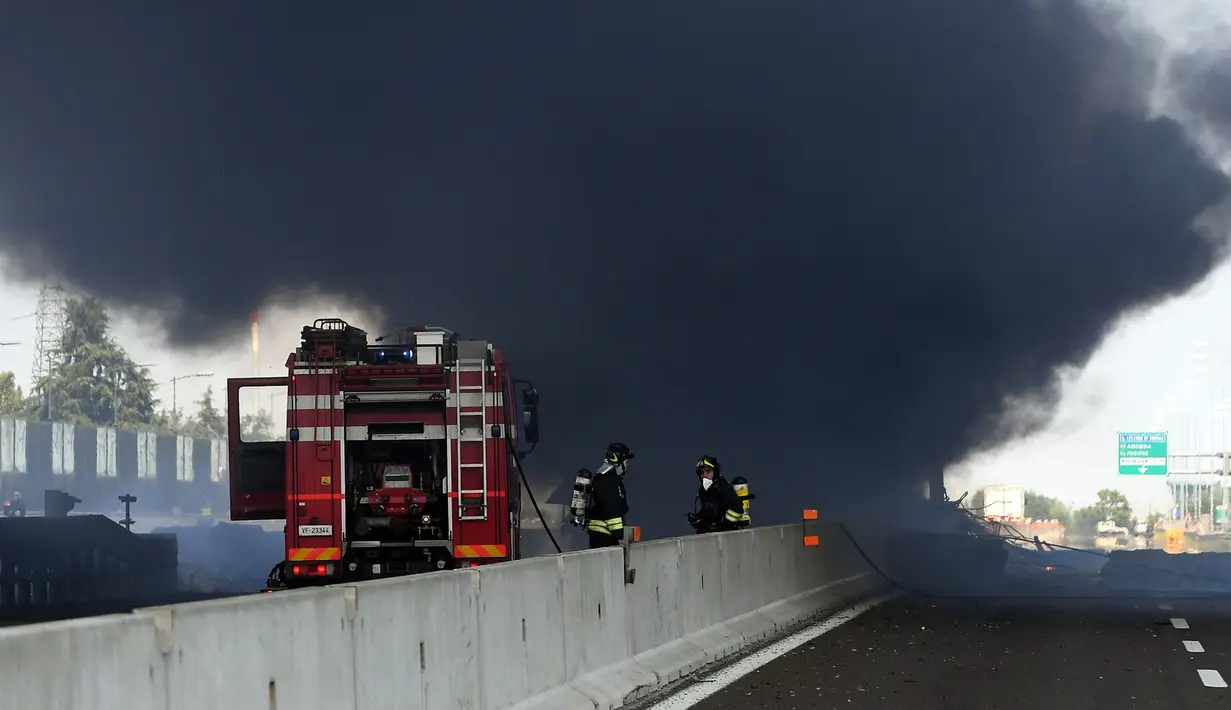 Petugas pemadam kebakaran berada di lokasi ledakan truk tangki yang membawa bahan mudah terbakar di jalan raya dekat kota Bologna, Italia, Senin (6/8). Kuatnya ledakan bahkan sampai menyebabkan jalan layang rusak. (AFP/Gianni SCHICCHI)