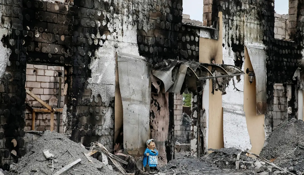 Sebuah patung terlihat di depan bangunan yang hangus terbakar, di desa dekat Kiev, Ukraina, Minggu (29/5). Sedikitnya 17 orang tewas orang tewas setelah kebakaran yang menghanguskan sebuah gedung yang digunakan sebagai panti jompo. (REUTERS/Gleb Garanich)