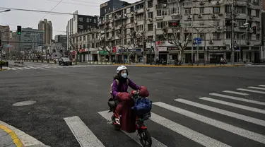 Seorang wanita mengendarai skuter di jalan yang sepi di distrik Yangpu, di Shanghai (28/3/2022). Jutaan orang di pusat keuangan China dikurung di rumah mereka pada Maret 28 ketika bagian timur Shanghai dikunci untuk mengekang wabah Covid terbesar di negara itu. (AFP/Hector Retamal)